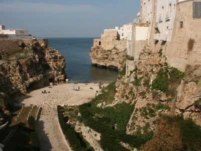 ...che permette l�affaccio sullo scenario pi� conosciuto e immortalato di Polignano: quello di Lama Monachile. Si tratta del letto di un antico torrente incastonato fra le pareti di roccia a strapiombo, la cui foce � rappresentata da una pittoresca spiaggia di sabbia e pietroline